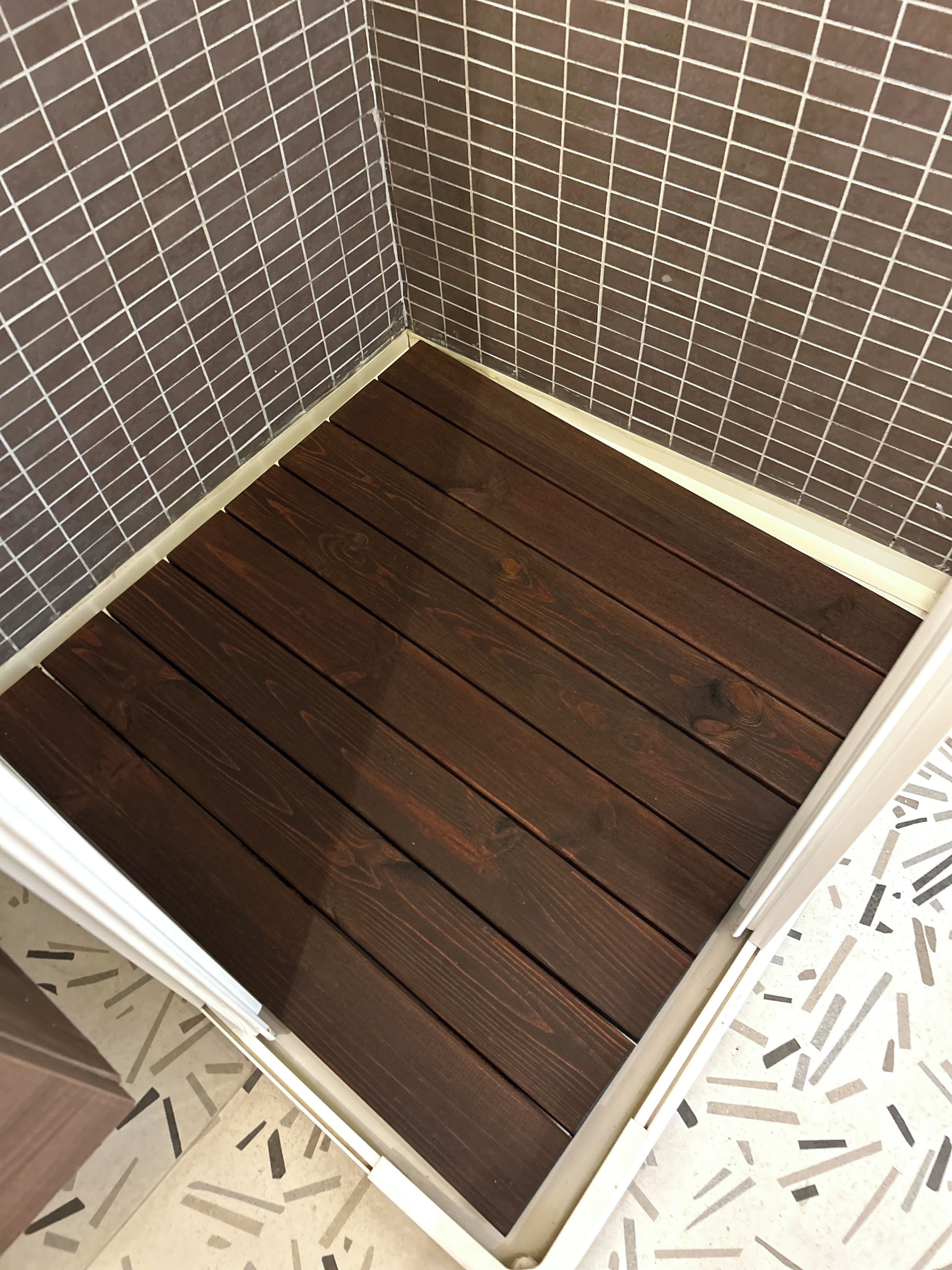 Une salle de bain avec un plancher en bois et des murs carrelés.