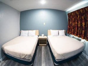 Una habitación con dos camas, una mesita de noche y una ventana con cortinas.