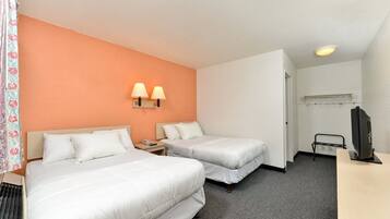 Une chambre d’hôtel avec deux lits, un bureau avec une télévision et une porte de salle de bain.