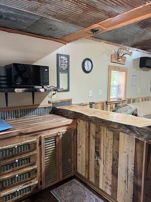 Une cuisine rustique avec un plan de travail en bois, un four à micro-ondes et une horloge au mur.