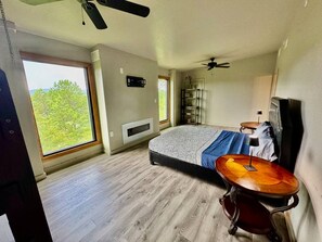 Een slaapkamer met een bed, bureau, stoel en raam.