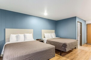 A hotel room with two beds, a wooden floor, and a blue wall.