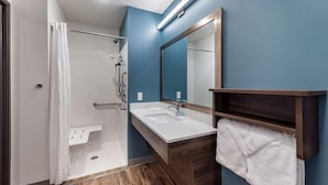 Un bagno moderno con doccia, lavandino e specchio.
