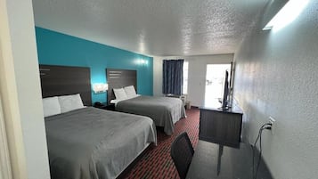 Una habitación de hotel con dos camas, un escritorio y una silla.