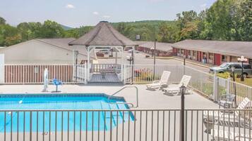 A pool area with a gazebo, lounge chairs, and a view of the surrounding buildings.