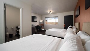 Een hotelkamer met twee bedden, een bureau, een stoel, een televisietoestel en een raam met uitzicht.