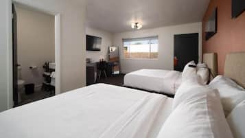 A hotel room with two beds, a desk, a chair, a television, and a window with a view.