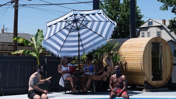 Zwembadgedeelte met een groot bord voor Motolodge, een houten vatstructuur en een gestreepte parasol.