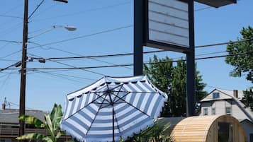 A swimming pool area with a large sign for Motolodge, a wooden barrel structure, and a striped umbrella.