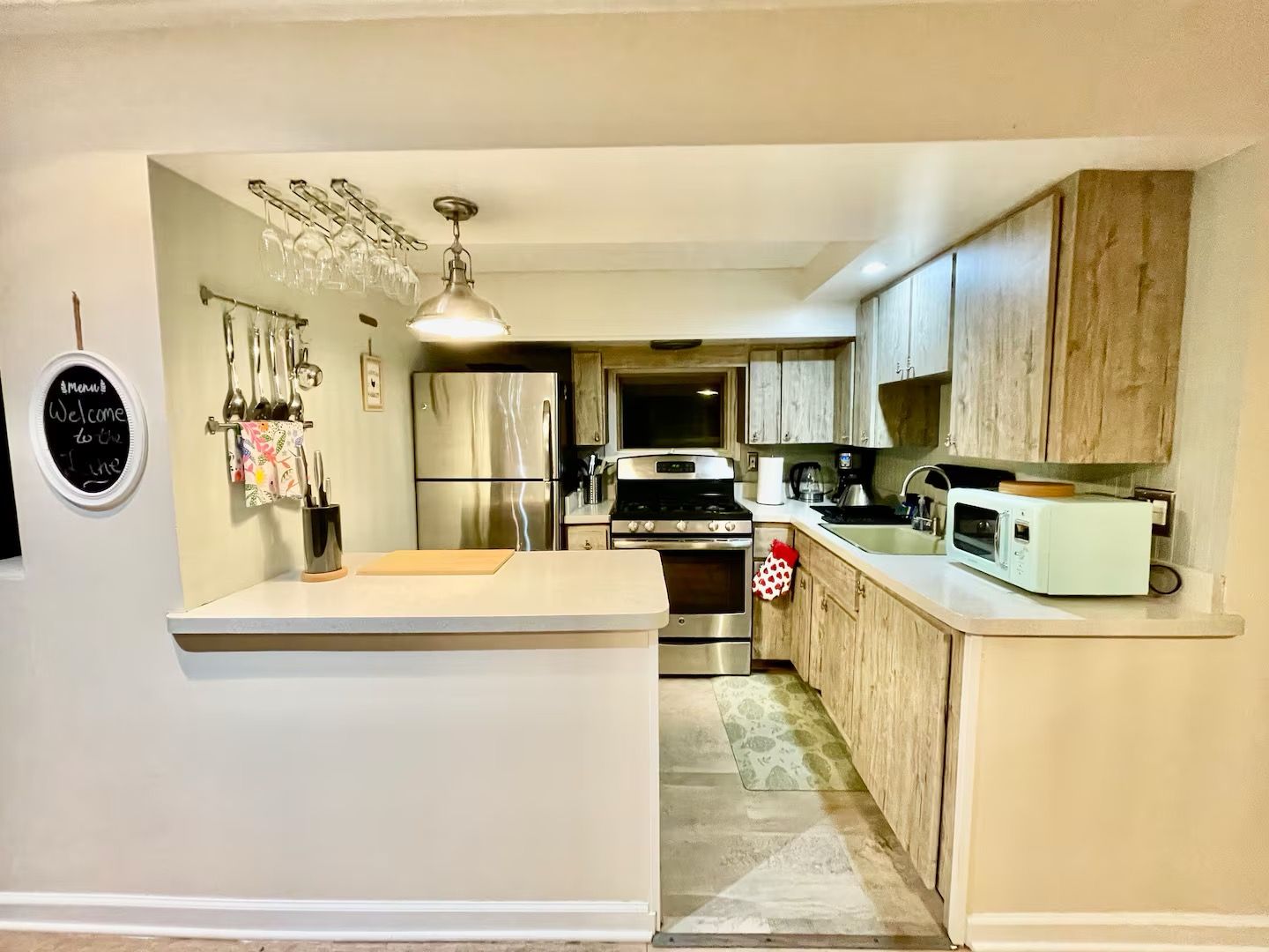 A compact kitchen with a central island, stainless steel appliances, and wooden cabinets.