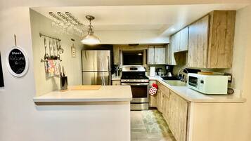 A compact kitchen with a central island, stainless steel appliances, and wooden cabinets.