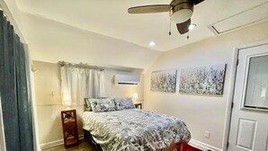 A bedroom with a bed, a ceiling fan, an air conditioning unit, and a door. - Cozy Summerville Cottage, Sleeps 6, Pet Friendly, Fully Fenced Back Yard (Rochester)