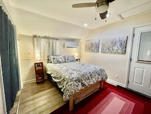 Een slaapkamer met een bed, plafondventilator, airconditioning en een deur.