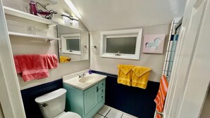 A bathroom with a toilet, sink, mirror, and towel racks. - Cozy Summerville Cottage, Sleeps 6, Pet Friendly, Fully Fenced Back Yard (Rochester)