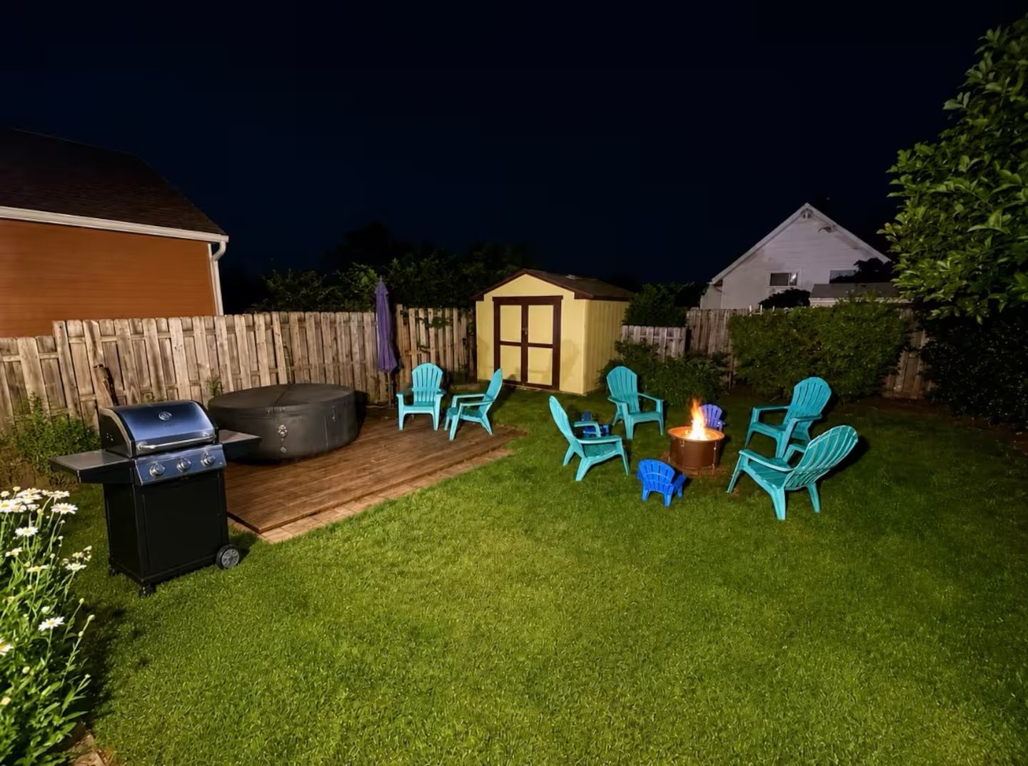 A backyard with a grill, outdoor seating, and a fire pit.