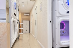 A hallway with a medical imaging machine, a refrigerator, and a door with a sign. - MIN HOSTEL CAPSULES (Madrid)