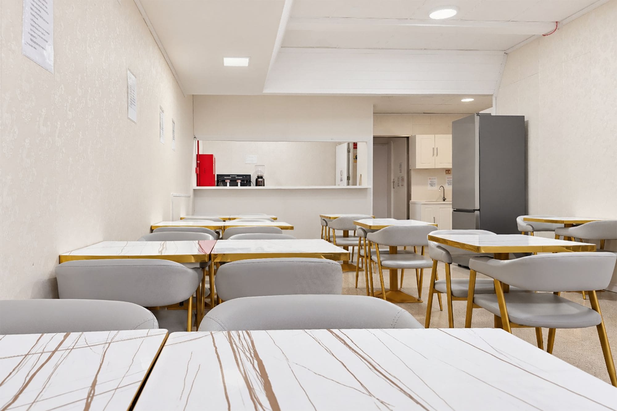 Une salle de classe moderne avec des murs blancs, des tables en bois et des chaises grises.