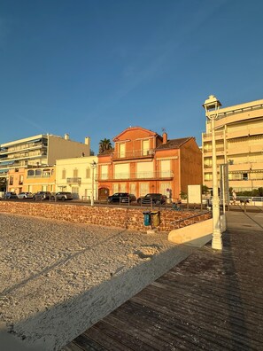 A coastal promenade with a stone wall, wooden boardwalk, and buildings with balconies. - Luxury beach front 3-bedroom Villa/apartment Cannes Palm Beach (Cannes)