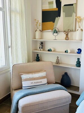 A room with a beige sofa, a cushion with 'ST. RAPHAEL' text, a wall with abstract art, and a Buddha statue. - Luxury beach front 3-bedroom Villa/apartment Cannes Palm Beach (Cannes)