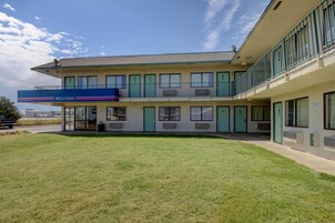 Un edificio de dos pisos con techo plano, habitaciones numeradas y una entrada acogedora.