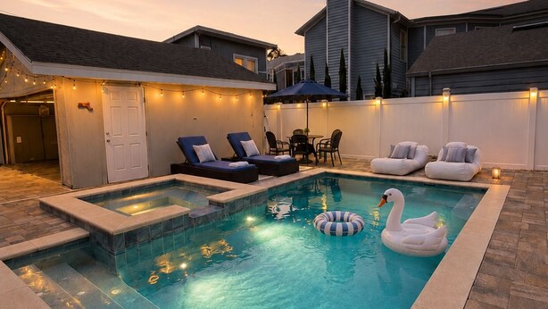 A swimming pool with lounge chairs and a swan float, surrounded by a patio area with string lights. - Beautiful bayshore Home Pool,Hot tub,Game room. (Tampa)