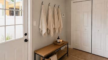 A hallway with a bench, a rug, and a door with a coat rack.