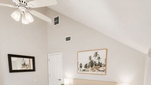 A bedroom with a bed, nightstands, a ceiling fan, a framed picture, and a door. - Beautiful bayshore Home Pool,Hot tub,Game room. (Tampa)