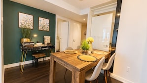 A dining area with a wooden table, chairs, and a dark green wall with floral artwork. - The Hazelton Horizon Downtown (Toronto)