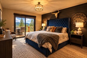Ein Schlafzimmer mit einem großen Bett, einer Kristallleuchter, einer Wanddekoration mit einem Stierkopf und Blick durch eine Schiebetür.