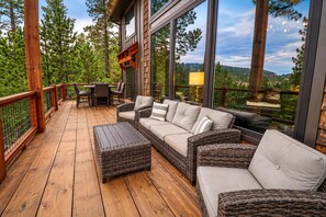 Una terraza de madera con mobiliario de mimbre, una mesa y sillas.