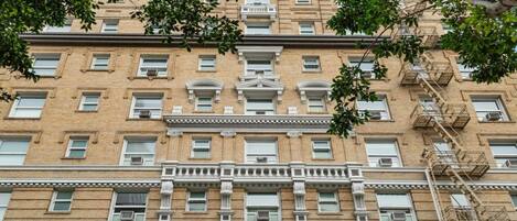 A multi-story building with a symmetrical facade, multiple windows, and fire escapes.