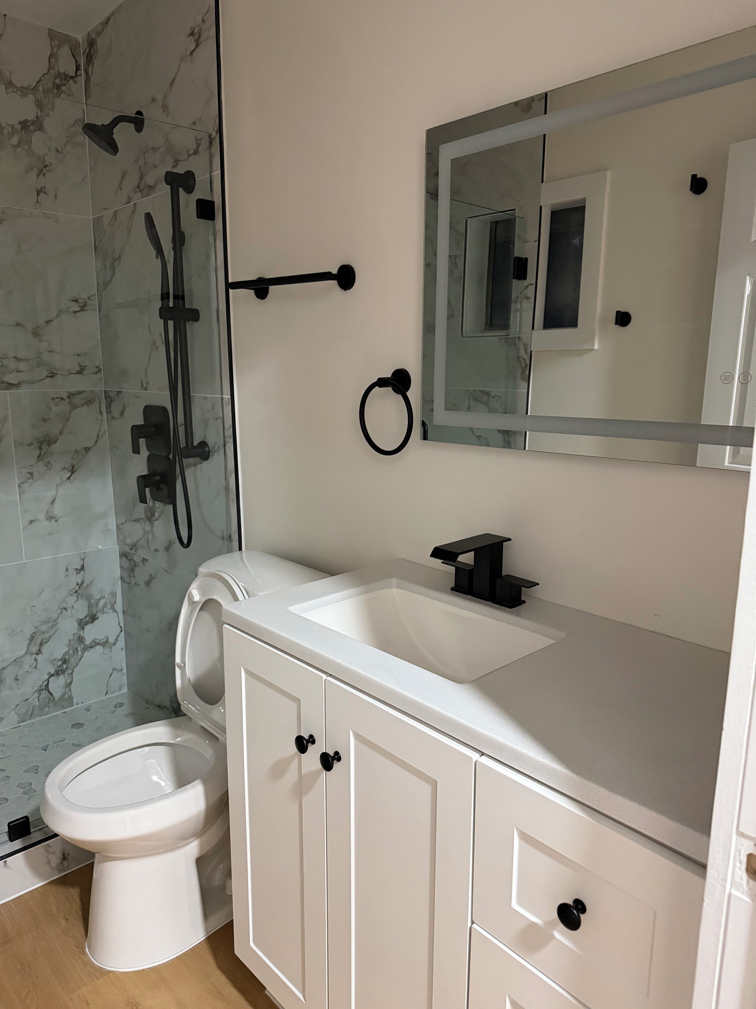 A bathroom with a white sink, a toilet, and a shower with a glass door.