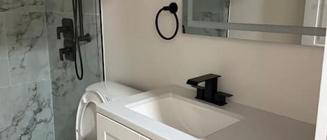 A bathroom with a white sink, a toilet, and a shower with a glass door.