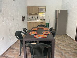 A compact kitchen with a gas stove, wooden cabinets, and a refrigerator.
