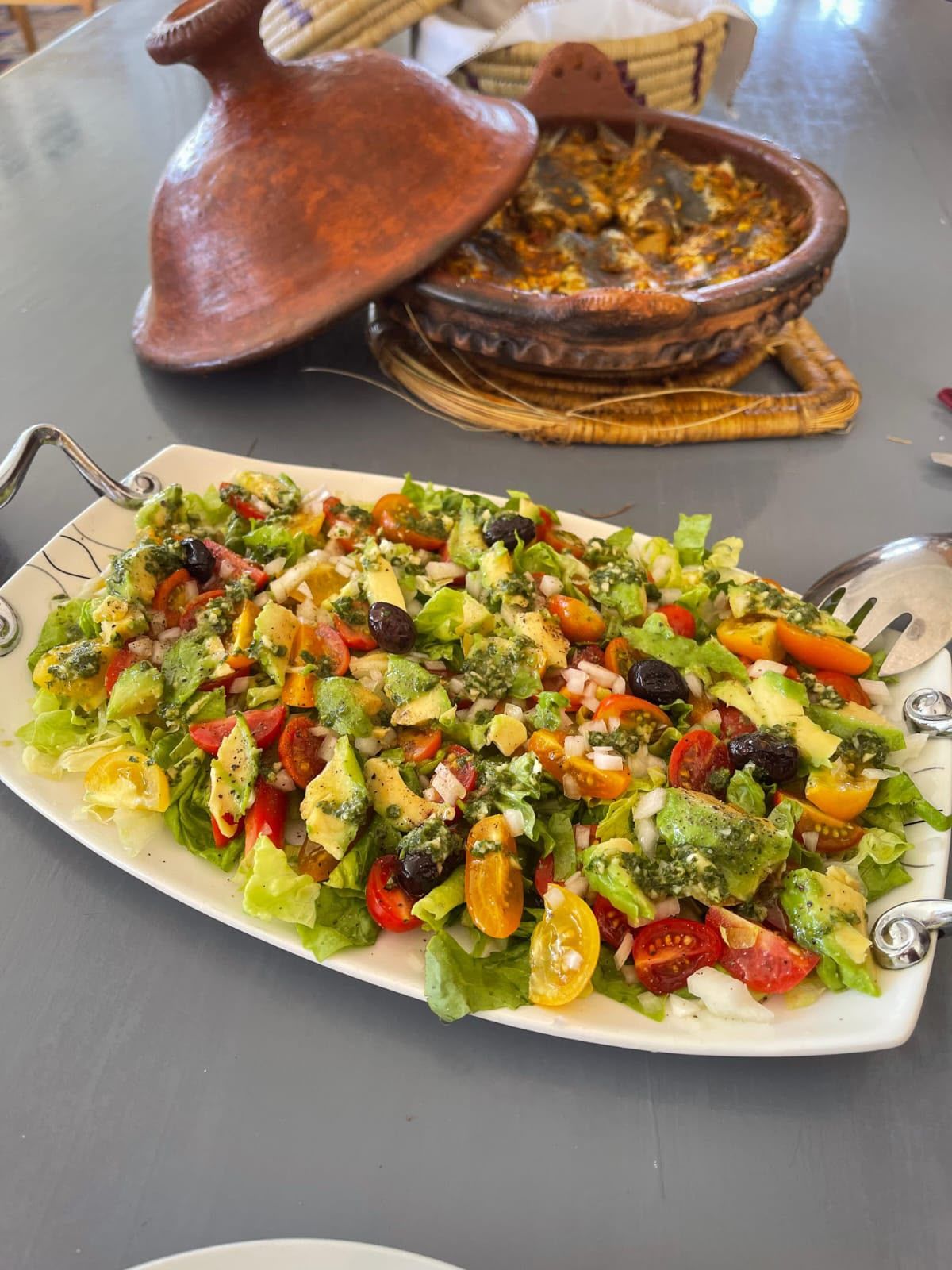 A table with a plate of mixed greens salad and a traditional Moroccan tagine pot.