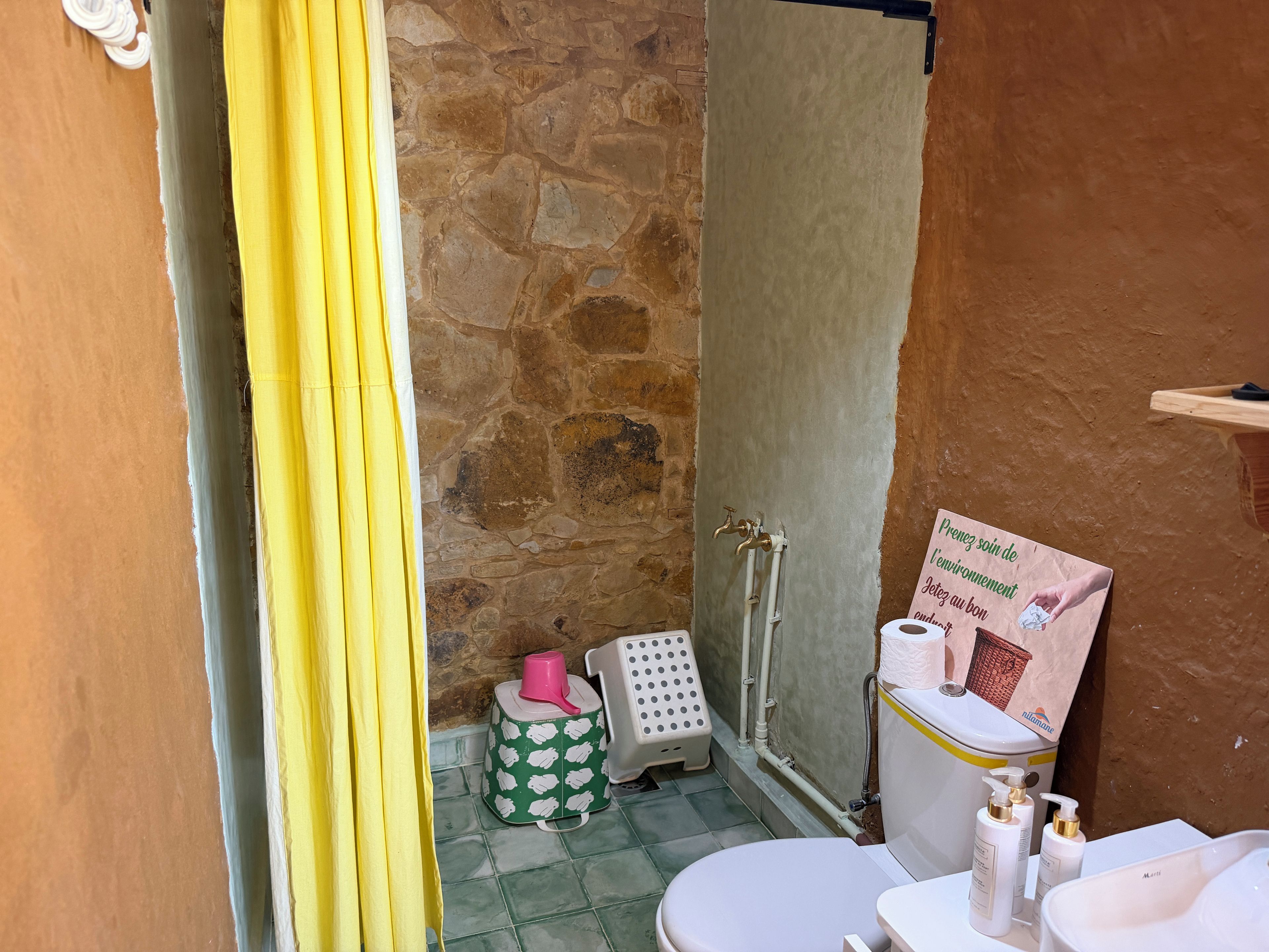 A bathroom with a toilet, sink, shower, and a towel rack.
