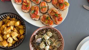 Una mesa con varios platos, incluyendo pan con tomate y hierbas, un bol de patatas asadas y un bol de mariscos.
