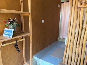 Una habitación con un estante de madera que sostiene un letrero y un jarrón con flores.
