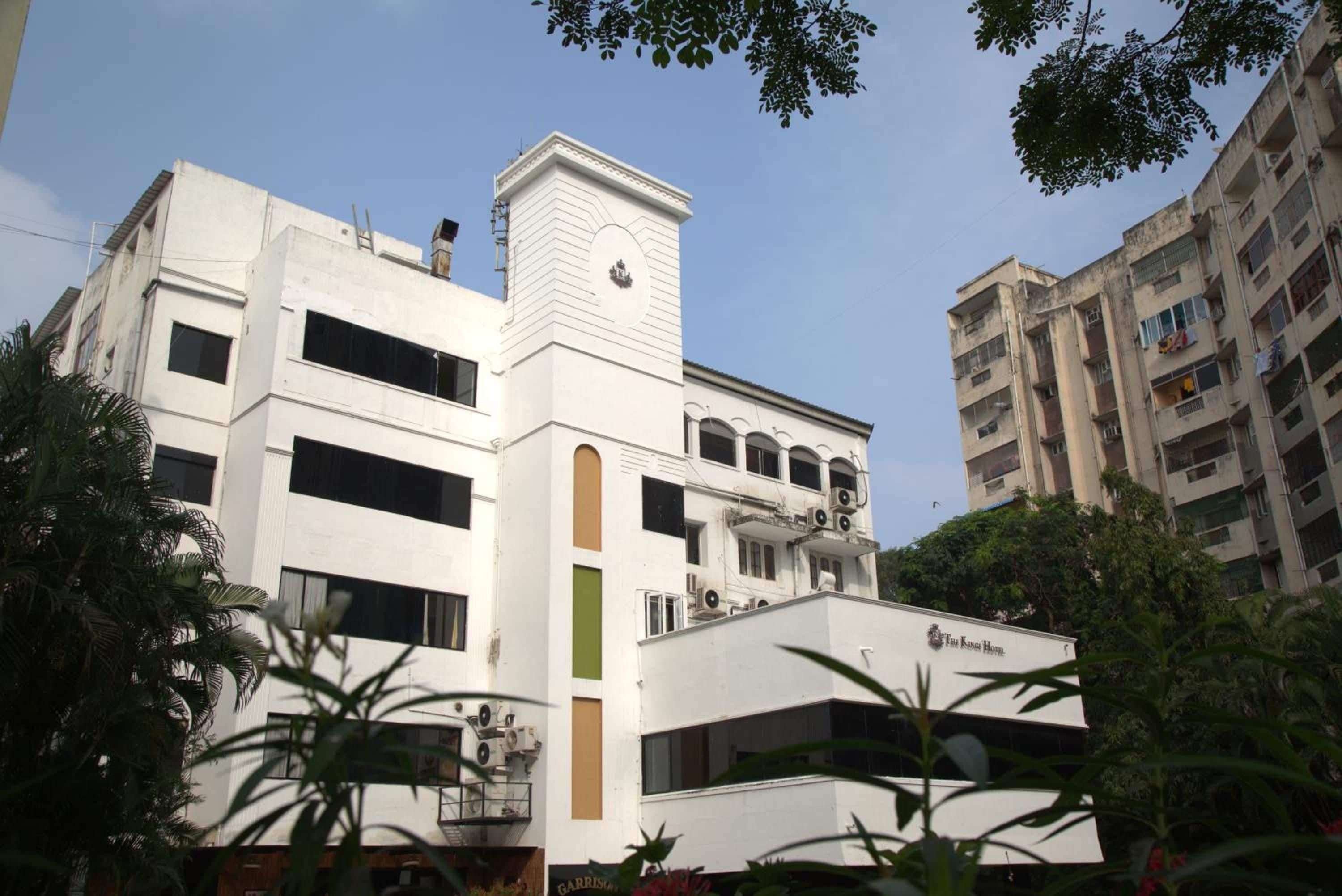 A multi-story building with a prominent white facade, several balconies, and a sign indicating it is a hotel.