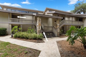A two-story building with a stone staircase and a balcony. - 657 Olde Camelot Circle (Haines City)