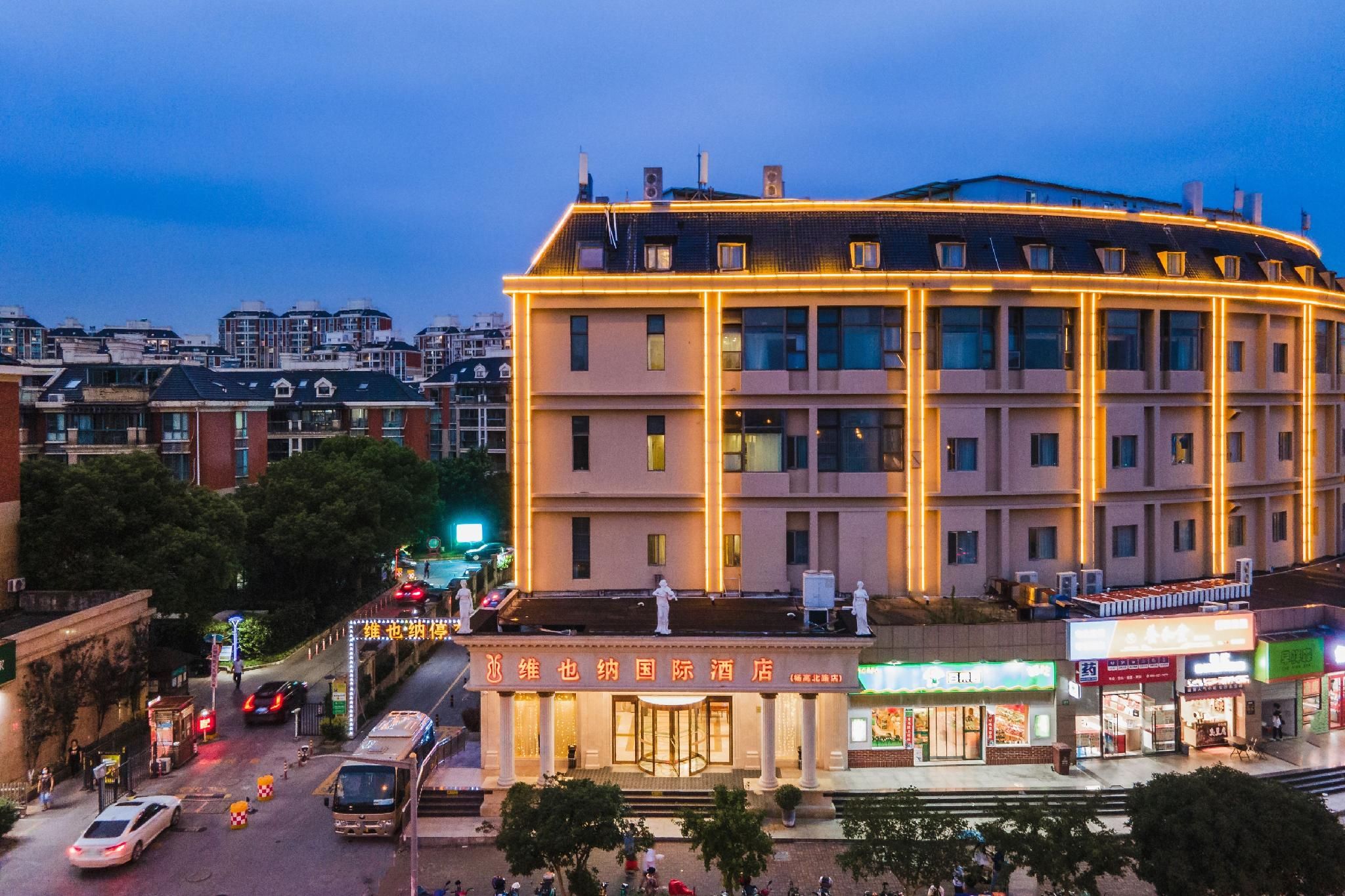 A multi-story hotel with a central courtyard, surrounded by other buildings.