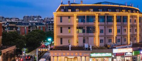 A multi-story hotel with a central courtyard, surrounded by other buildings.