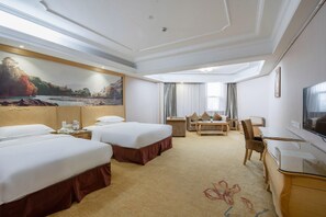 Habitación de hotel con dos camas, un escritorio, una silla, un televisor y un ventanal con cortinas.