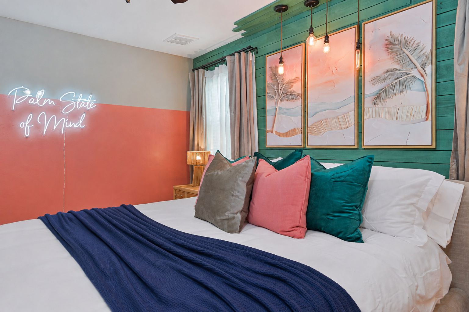 A hotel room with a bed, pillows, a neon sign, artwork, and a nightstand.