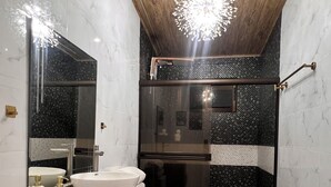 Un bany modern amb sostre de fusta, un lavabo independent, un espai de banyera amb dutxa de vidre i terres de marbre.