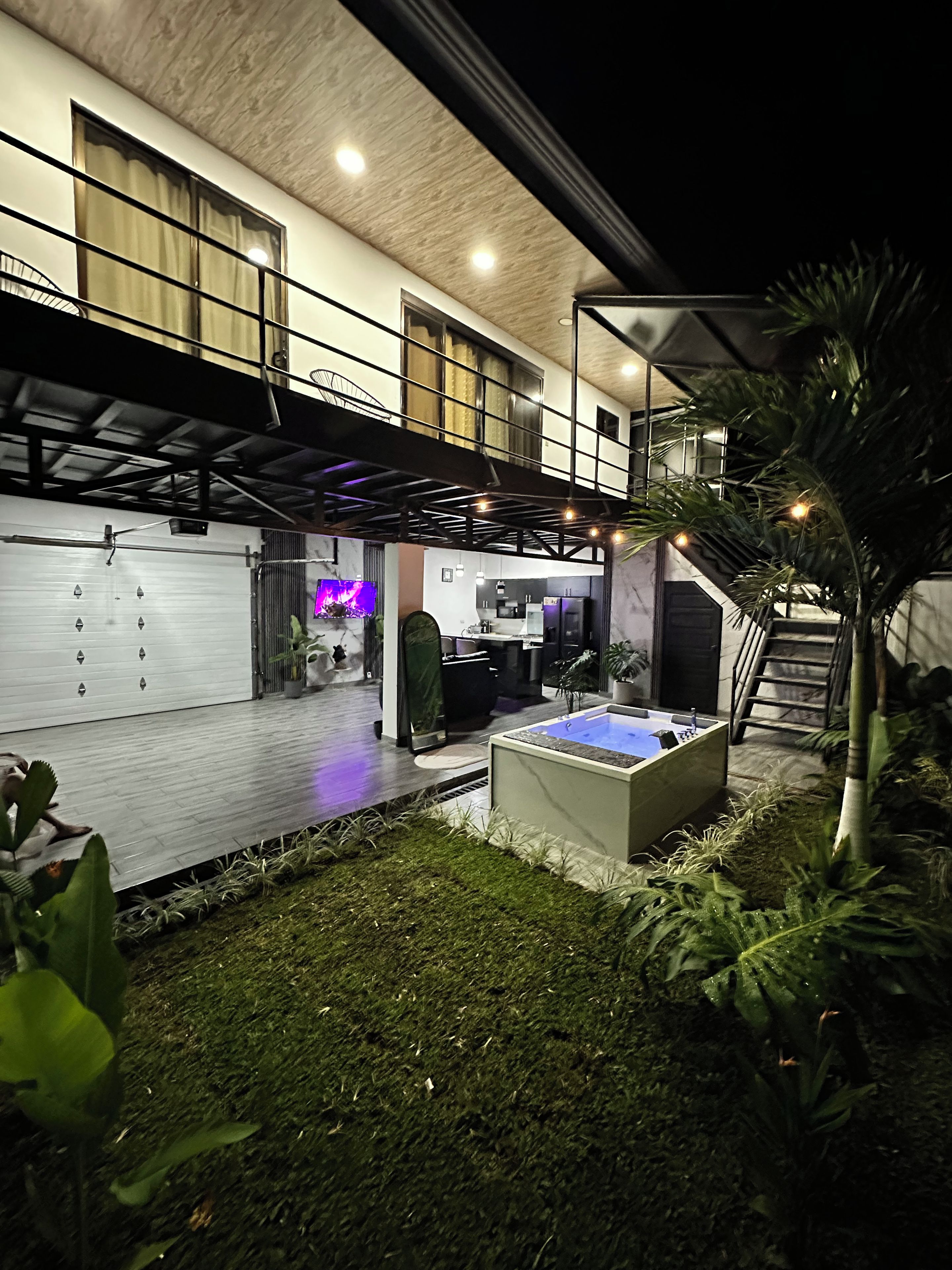 A modern house with a spacious deck, a hot tub, and a well-maintained garden.
