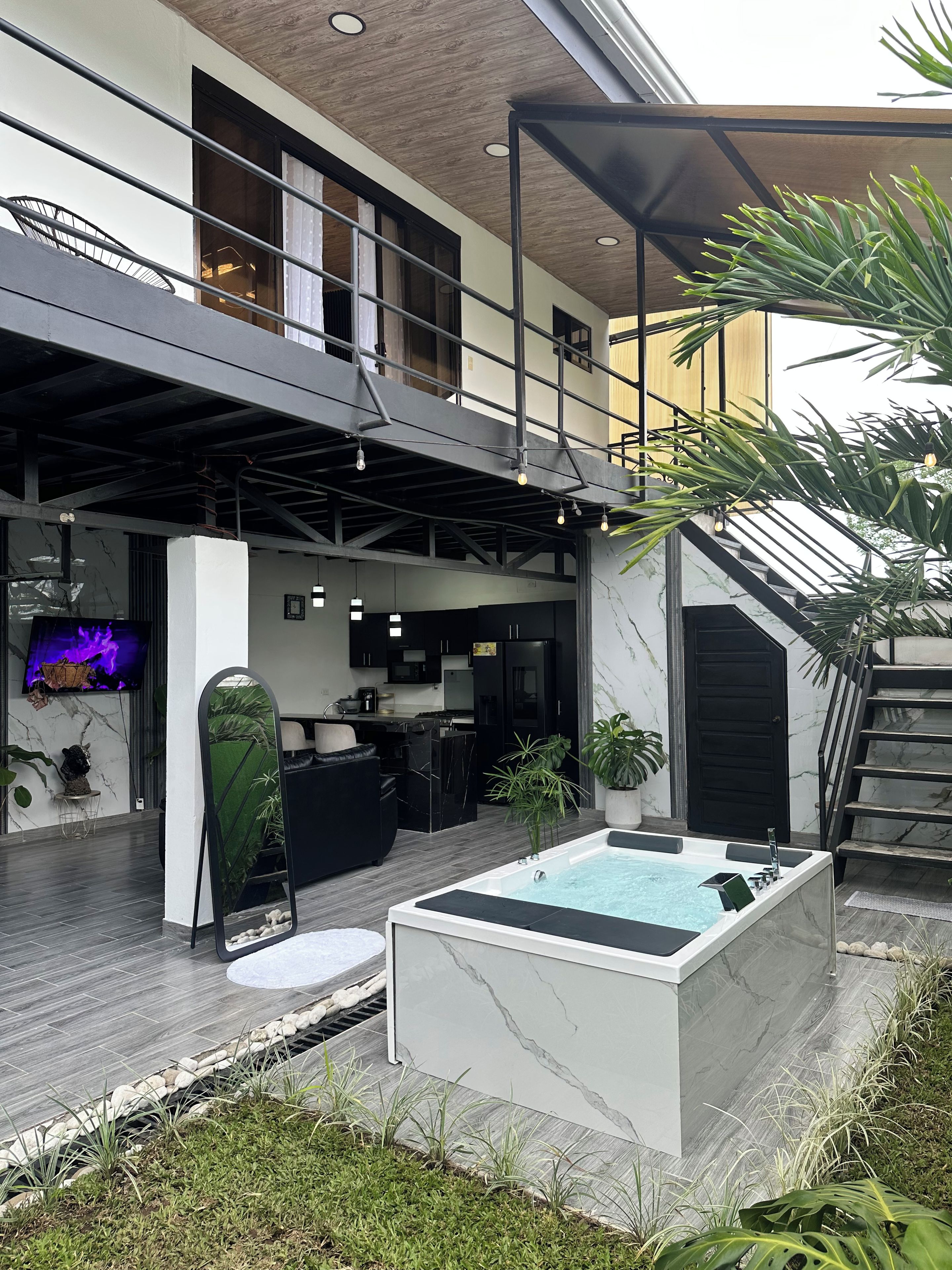 Un espace de vie extérieur moderne comprenant un jacuzzi, une cuisine et un balcon.