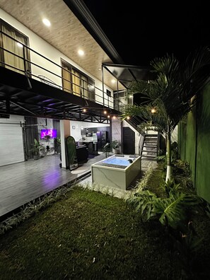 A modern outdoor space with a hot tub, a staircase, and a kitchen area.