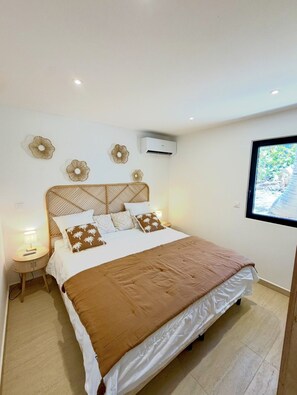 A bedroom with a bed, a nightstand, wall decor, an air conditioning unit, and a window with a view. - SEA VIEW MULLET BAY Villa – Brand-new waterfront villa in Oyster Pond (Oyster Pond)