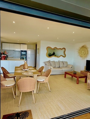 A modern living space with a dining area, sofa, and a kitchen in the background. - SEA VIEW MULLET BAY Villa – Brand-new waterfront villa in Oyster Pond (Oyster Pond)